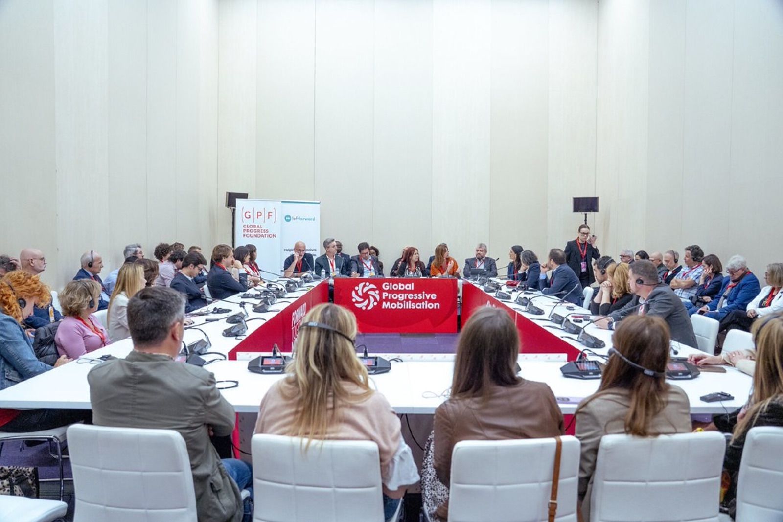 A LeftForward panel at the Global Progressive Mobilisation in Barcelona, with speakers seated around a horseshoe table and a LeftForward banner behind them